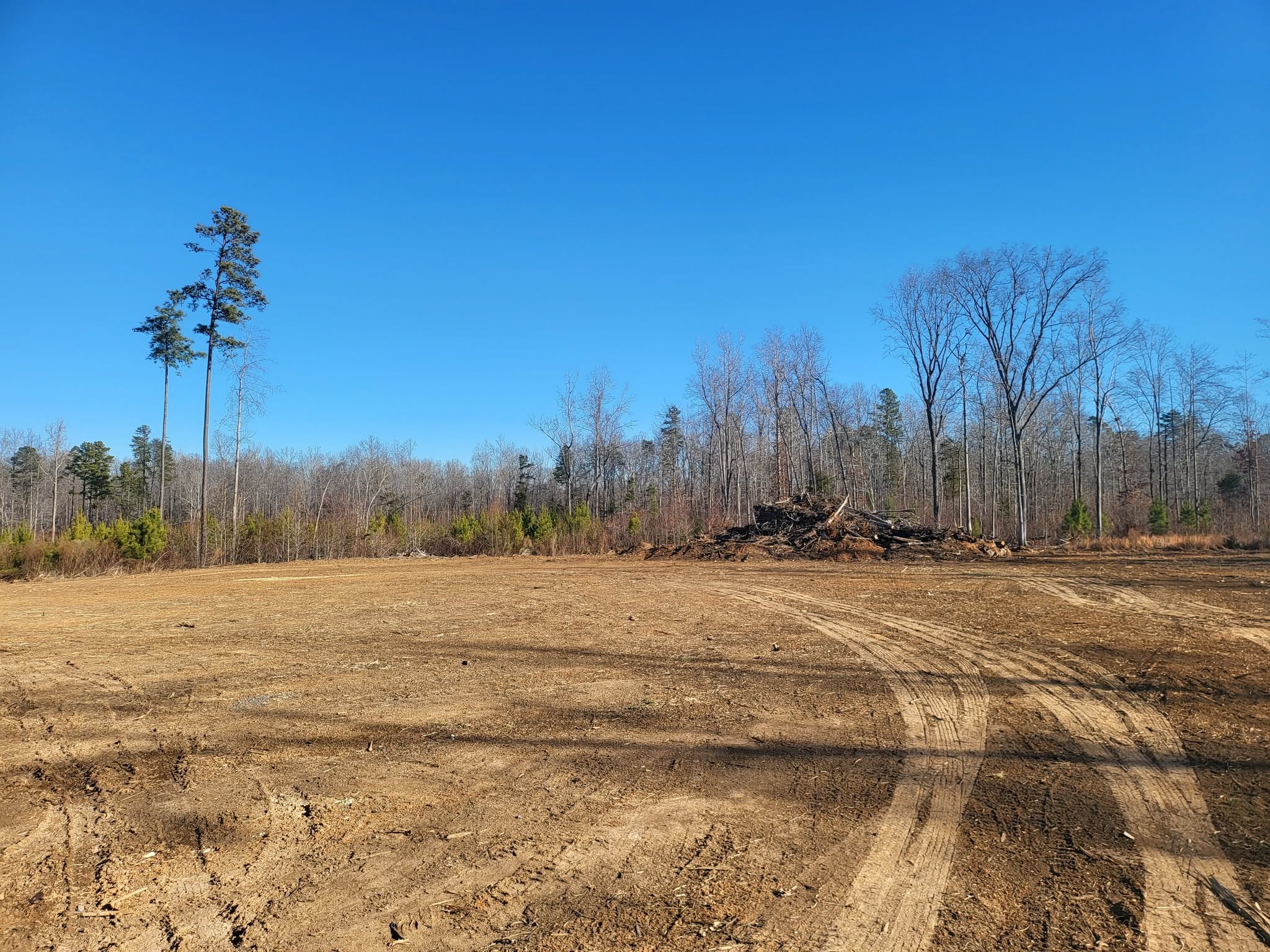 Large cleared and graded building site surrounded by woods